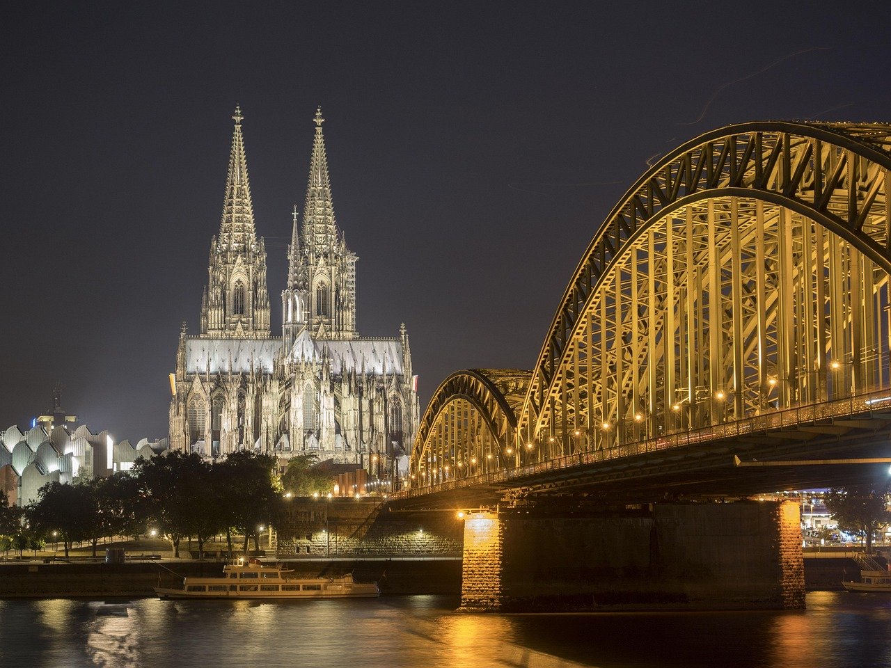 Blick über den Rhein entlang der Rheinbrücke auf den Kölner Dom bei Nacht.