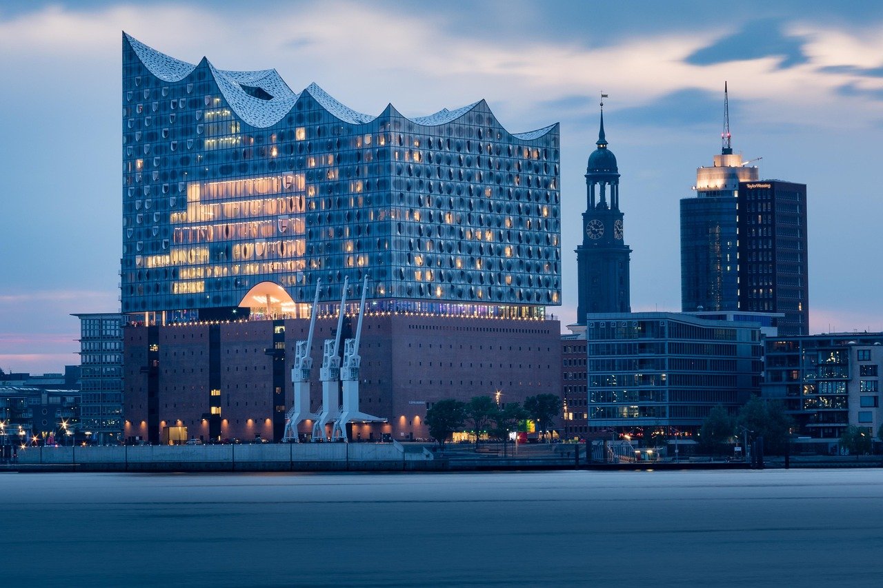 Blick über die Elbe auf die Elbphilharmonie in der Dämmerung. Der Michel im Hintergrund.